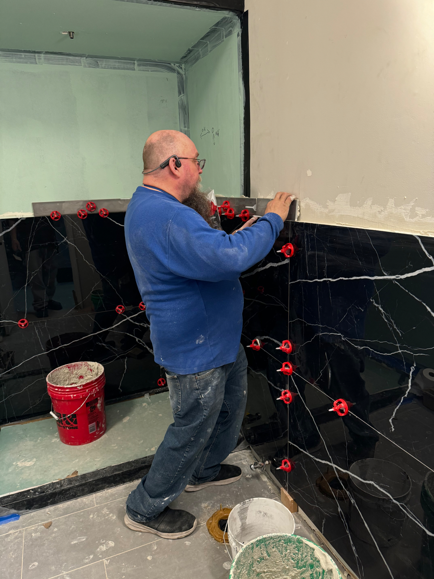 Large-format marble tile set on a full bathroom rebuild after rough-in inspection.